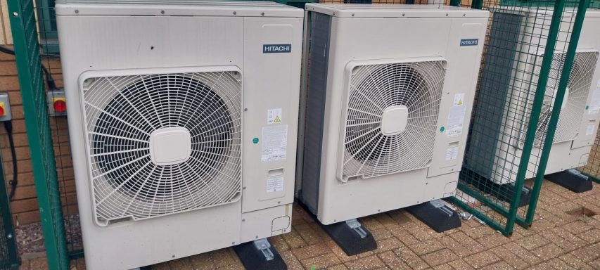 Two outdoor air conditioning units installed on a paved surface.